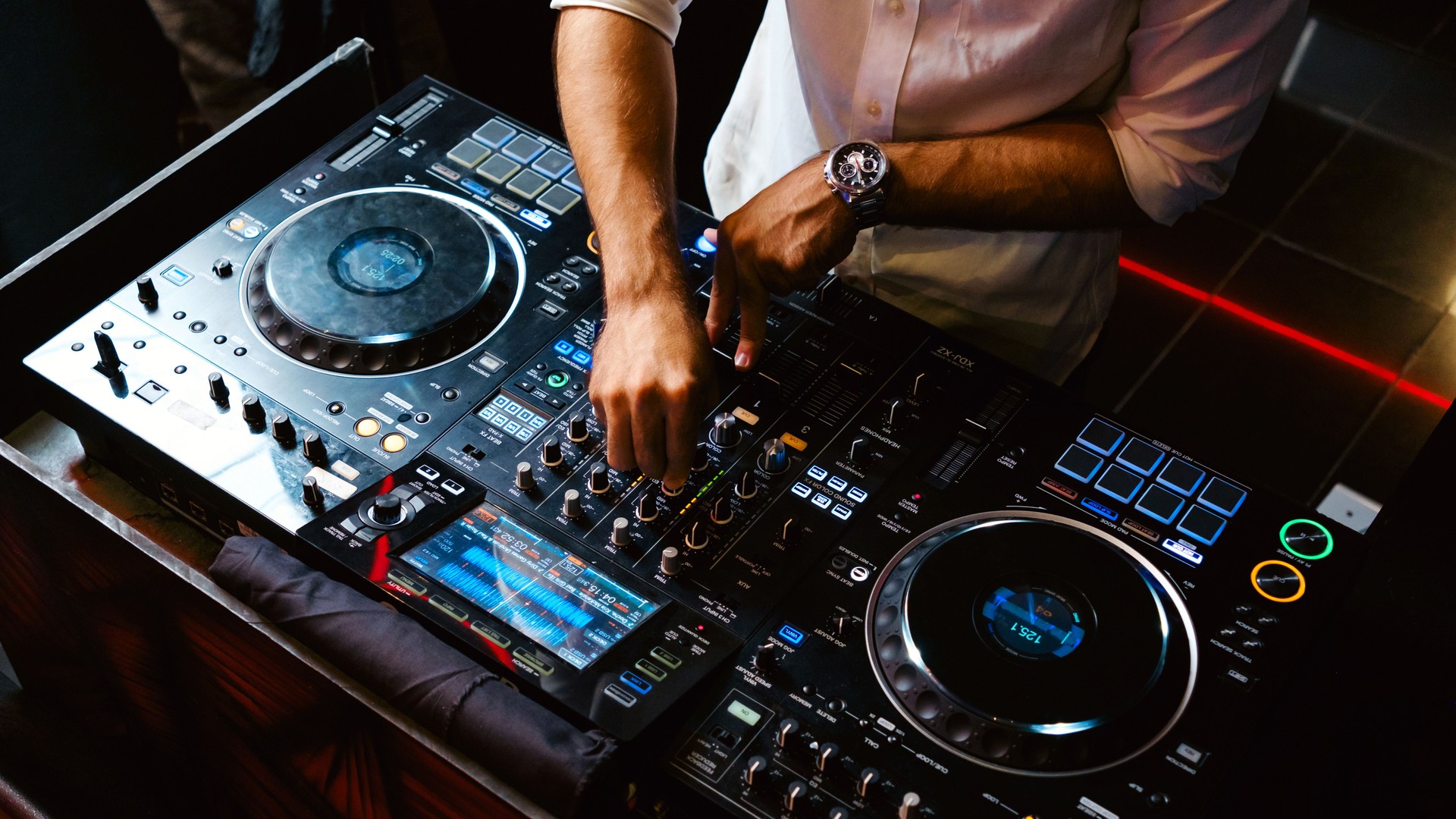 Close up DJ plays live set and mixing music on turntable console in the night club. Disc Jokey Hands on a sound mixer station at club party. DJ mixer controller panel for playing music and partying.