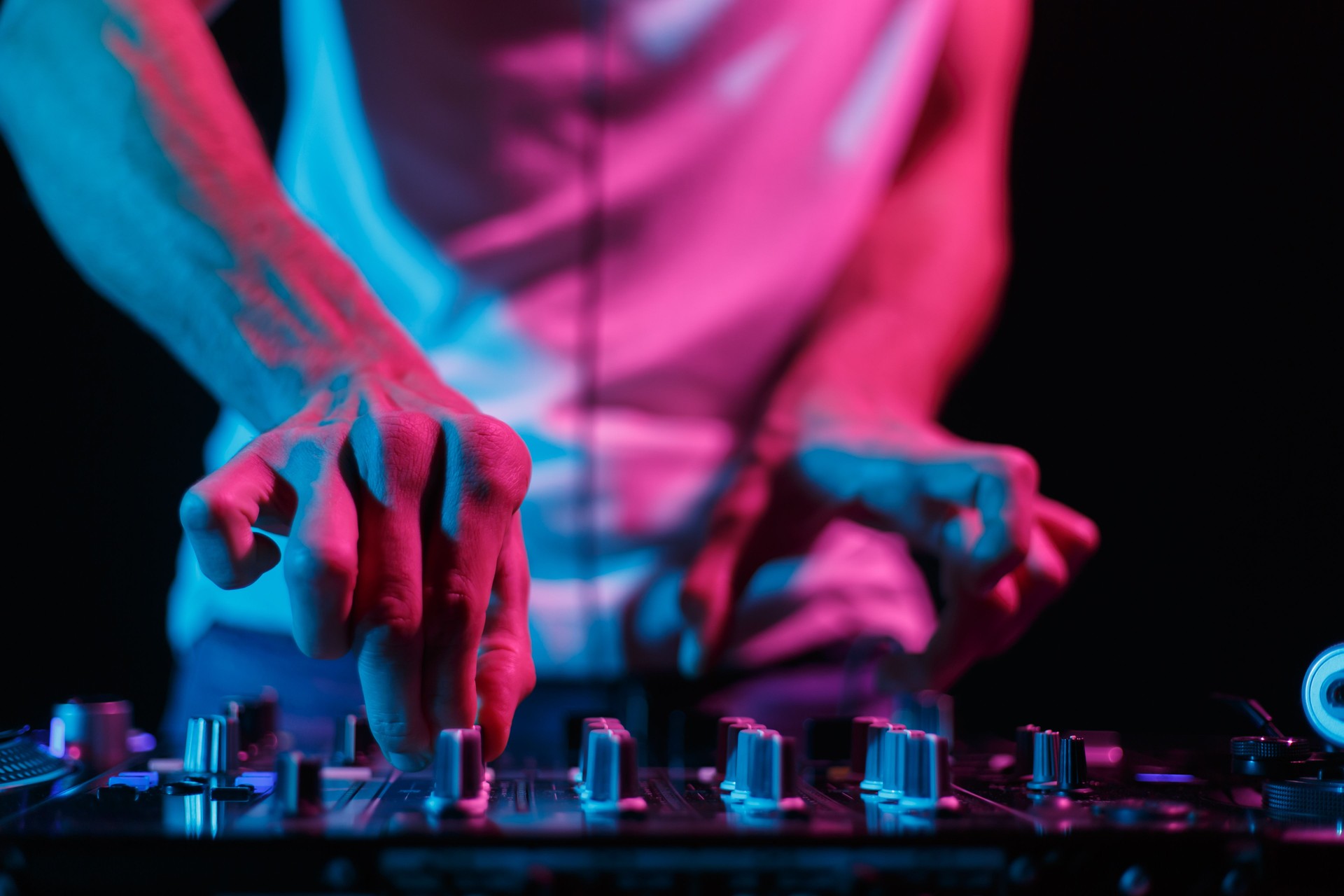 Party DJ mixing musical tracks. Close up photo of club disc jockey adjusting volume on sound mixer